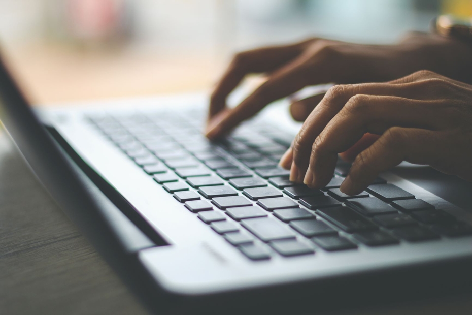 A close up of an individual's hands over a laptop keyboard as they respond to an online survey.
